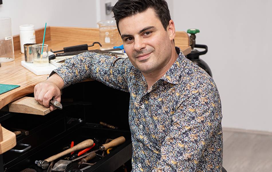 Cosimo Mirarchi holding his flat nose pliers beside his worktable.