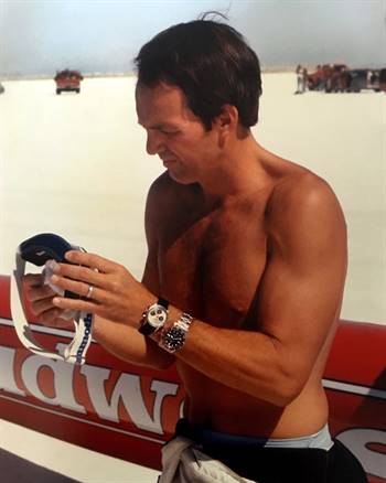 Old snapshot of Stan Barrett wearing a Rolex Daytona and Rolex GMT in front of a Budweiser Rocket Car. Source: Rolex Magazine