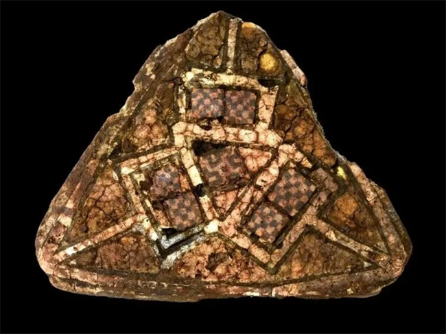 A triangular brooch with glass mosaic and gold enamel, believed to be from Ireland or England, was found in the grave within a rock crevice.