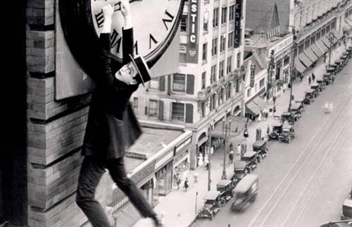 Harold Lloyd dangling from a large clock in his iconic scene from Safety Last!, a 1923 silent romantic comedy.